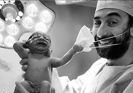 Foto della speranza, neonato strappa la mascherina al medico