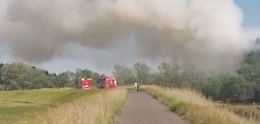 Vasto incendio in un'area verde, denso fumo visibile dalla provinciale