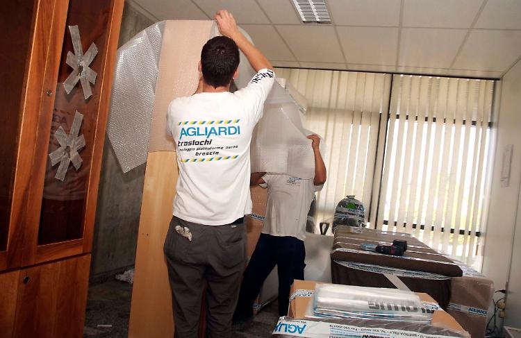 Operai in tribunale mentre imballano mobili e faldoni