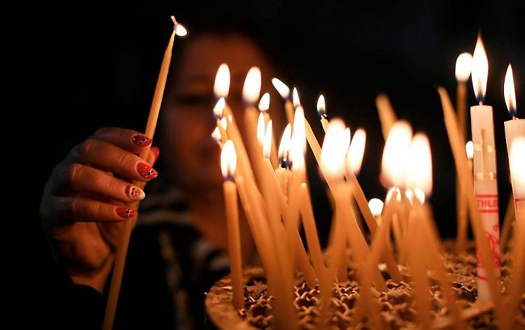 Candele accese a scrocco e il parroco toglie i lumini