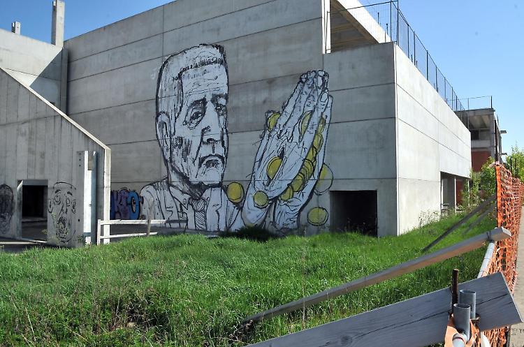 Soldi tra le mani giunte, murale con Formignoni sulla ex scuola di Cl