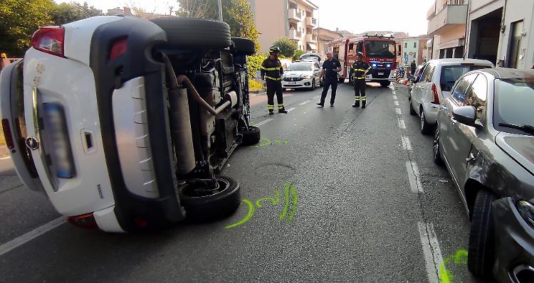 Perde il controllo dell'auto, sbatte contro un veicolo in sosta e si ribalta
